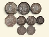 six silver coins of various sizes and shapes are arranged on a white surface
