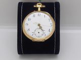 a small gold pocket watch on a black velvet stand