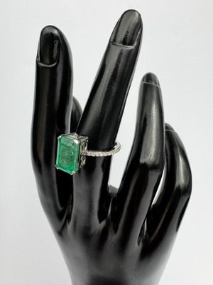 une main noire ornée d'une bague sertie d'une pierre verte
