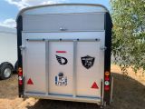 the back of a trailer with stickers on it is parked in a field