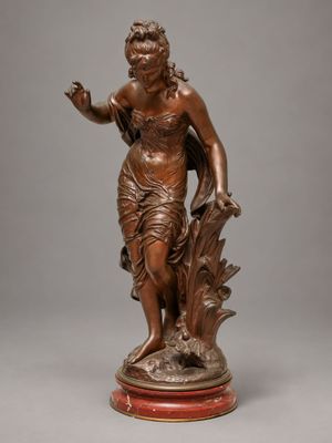 une statue antique en bronze représentant une femme tenant un oiseau, posée sur un socle