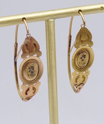 une paire de boucles d'oreilles posées sur un support en or