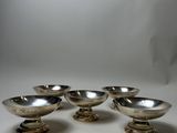 four silver plated bowls on pedestals on a white surface