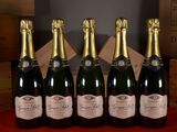 six bottles of champagne are lined up on a red table