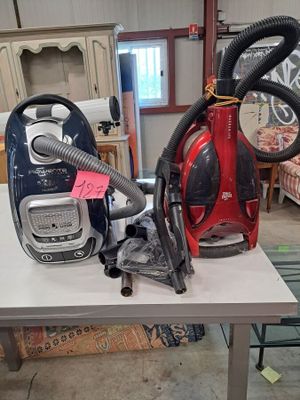 two vacuums sitting on a table in a room