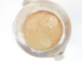 a white vase with a brown lid on a white table