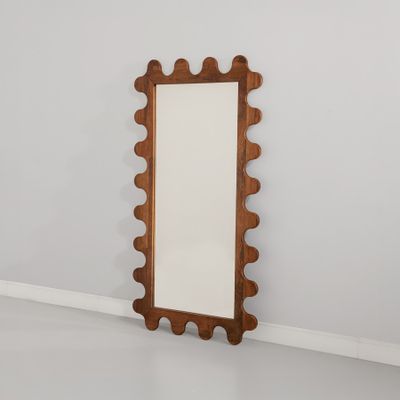 un miroir en bois posé sur un sol blanc, près d'un mur
