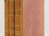 three old books sitting on top of each other on a white surface