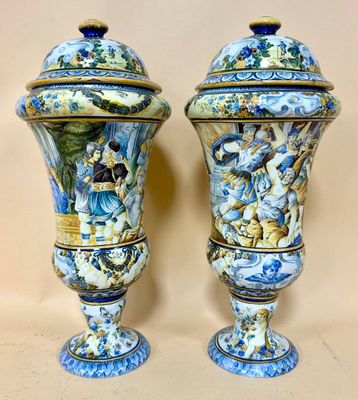pair of blue and white vases with figures on them sitting on a table