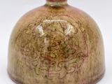 un vase brun posé sur une surface blanche
