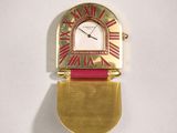 an image of a gold and red clock hanging on a wall