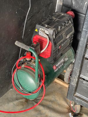 an image of a green air compressor in a garage