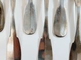six spoons and a fork on a white surface