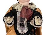 une poupée assise par terre, vêtue d'un costume