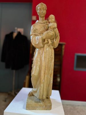 statue d'une femme tenant un enfant dans ses bras, posée sur un socle dans une pièce