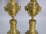 pair of antique brass urns on pedestals on grey background