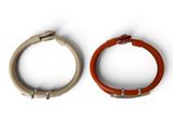 two pieces of leather and metal bracelets on a white surface