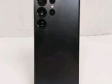 a close up of the back of a black phone on a white surface
