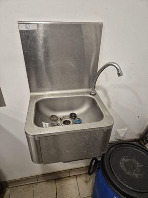 a stainless steel sink with a faucet in the corner of the room