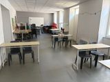 de nombreuses tables et chaises dans une salle équipée d'un tableau blanc