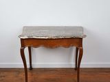 une vieille table en bois avec un plateau en marbre, posée sur un parquet en bois massif