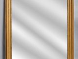 a gold framed mirror against a gray wall