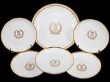 six assiettes blanches et dorées, ornées de bordures dorées sur fond noir