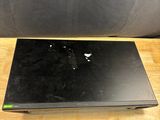 un ordinateur portable noir posé sur une table en bois, avec une chaise noire en arrière-plan