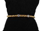 a gold and diamond bracelet on a black velvet pillow
