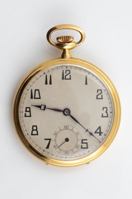 a close up of a gold pocket watch on a white surface