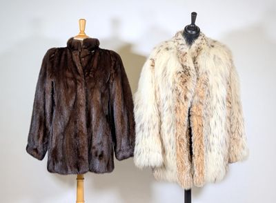 pair of fur coats on a mannequin stand against a white wall
