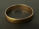 gros plan d'une bague en or sur une surface noire