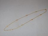 a close up of a gold necklace on a white surface