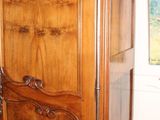 a wooden armoire in a room with pictures on the wall