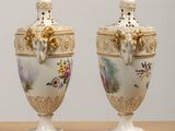 two vases are sitting on a wooden table with a wall in the background