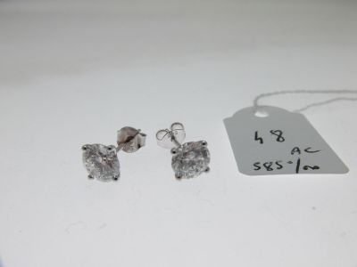une paire de boucles d'oreilles en argent et une étiquette de prix posée sur une table blanche