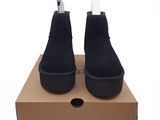 des bottines en daim noir à semelles blanches posées sur une boîte en carton