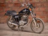 a black motorcycle parked in front of a brick wall