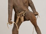 une statue en bois représentant un homme avec une corde autour des chevilles