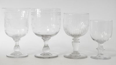 four wine glasses are lined up in a row on a white surface