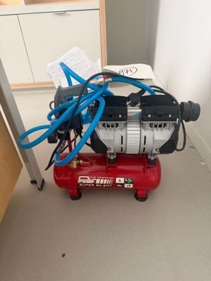 a red air compressor sitting on the floor in a room