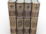 four old books stacked on top of each other on a white surface