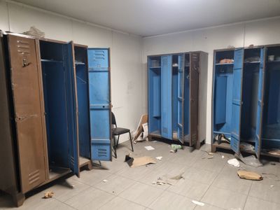 several blue lockers in a room with a chair in it