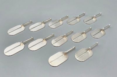 six pairs of silver plated spatulas on a gray surface