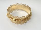 a close up of a gold bracelet on a white surface