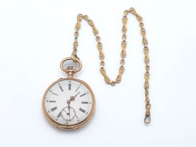 une montre de poche en or avec une chaîne, posée sur une surface blanche