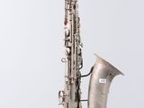 an old silver saxophone hanging from a string on a white wall
