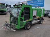 a green garbage truck parked in front of a building