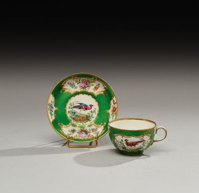une tasse et une soucoupe vertes et dorées ornées d'un oiseau