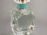 crystal perfume bottle with a green top on a gray surface